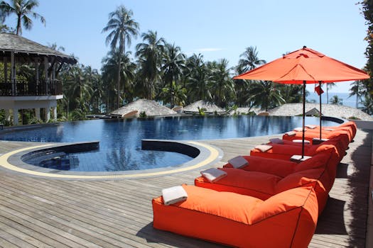 Home Relax at a tropical resort with sun loungers and palm trees by the pool.
