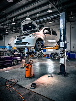 Home A car is lifted on a hydraulic lift in a well-equipped auto repair shop.