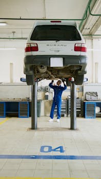 Home A professional mechanic checks a car on a lift in an auto repair shop.