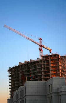 Home Tower crane on a high-rise building under construction at sunset, showcasing modern urban development.